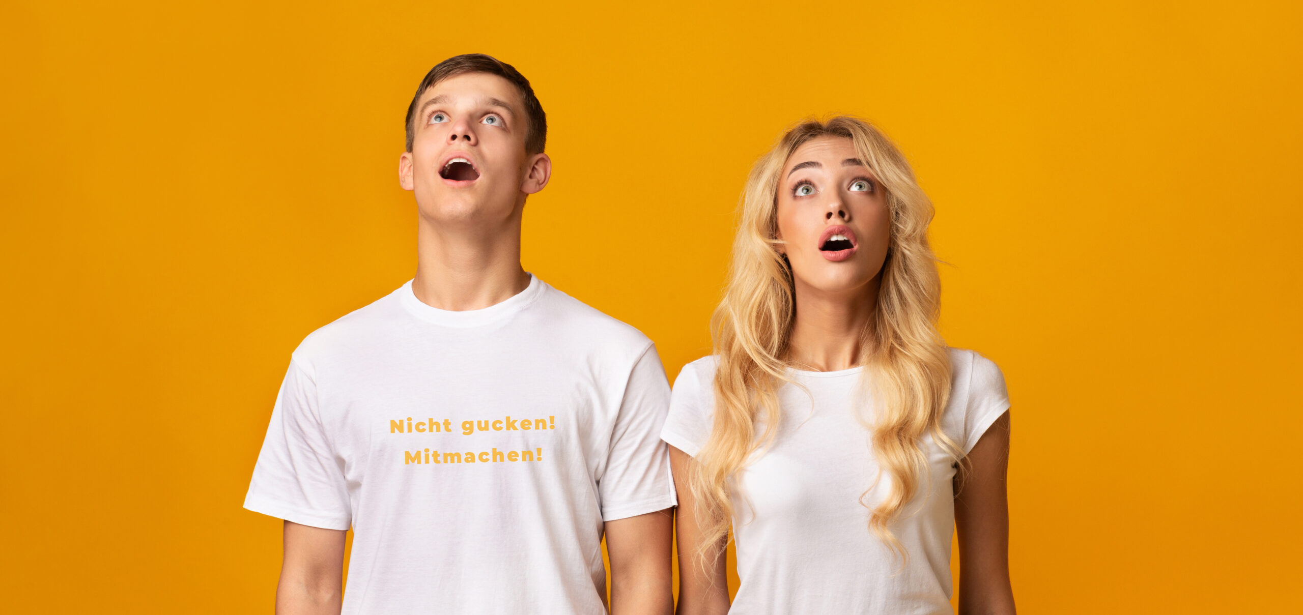 Amazed guy and girl looking upwards at something with open mouth